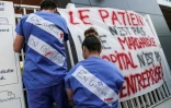 Des soignants des urgences de l'AP-HP attachent des banderoles à l'entrée de La Pitié-Salpêtrière à Paris, le 15 avril 2019, pour protester contre leurs conditions de travail.