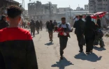 Un Palestinien court en portant une fille blessée après une frappe israélienne dans le quartier de Zeitoun à Gaza-ville, le 13 avril 2025