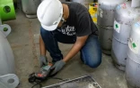 Le technicien Ari Sobaruddin de la société Recoolit vérifie le gaz réfrigérant stocké dans des bouteilles dans l'entrepôt de l'entreprise à Jakarta, le 12 juin 2025 en Indonésie