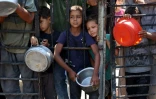 Des enfants palestiniens attendent de recevoir de la nourriture devant une organisation de charité locale distribuant du riz cuit, dans la ville de Gaza, le 23 août 2025