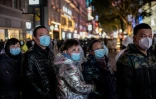 Des habitants regardent un écran 3D géant le 10 janvier 2021 à Wuhan, à la veille du premier anniversaire du 1er décès de coronavirus annoncé par la Chine
