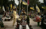 Une jeune femme se recueille devant la tombe d'un soldat au cimetière de Sumy, dans le nord-est de l'Ukraine le 11 juin 2025