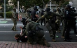 Des membres de la police des frontières plaquent au sol une manifestante à Santa Ana, en Californie, près du bureau des Services de l'Immigration, le 9 juin 2025, lors de protestations contre la politique migratoire de Donald Trump