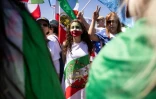 Une manifestante envelopée dans un drapeau utilisé par l'Iran avant la révolution islamique, autour du SoFi Stadium à Inglewood, près de Los Angeles, le 15 juin 2026