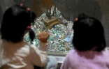 Deux fillettes japonaises regardent la grosse pince saisir des déchets voués à l'incinération, depuis le bar Gomi Pit à Tokyo, le 18 janvier 2019