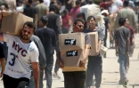 Des Palestiniens déplacés transportent des sacs d'aide, de retour d'un centre de distribution de la GHF dans le centre de la bande de Gaza, le 29 mai 2025