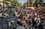 Des membres de l'unité militaire Capsat patrouillent à bord d'un véhicule blindé alors que les habitants se rassemblent pour une cérémonie en hommage aux manifestants tués lors des manifestations antigouvernementales à Antananarivo, le 12 octobre 2025 à Madagascar