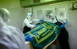 Des personnels funéraires en combinaison de protection préparent le corps d'une personne décédée du coronavirus à la morgue du cimetière d'Istanbul, le 21 mai 2020 en Turquie