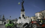 Des employés municipaux disposent des sacs de sable autour d'un momument pour le protéger des bombardements russes, le 26 mars 2022 à Kharkiv (est de l'Ukraine)