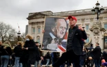 Un homme pose avec le portrait du prince Philip devant le Palais de Buckingham, au lendemain de son décès, le 10 avril 2021 à Londres