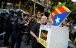 Une personne porte une urne symbolique face à des policiers espagnols en soutien au référendum catalan. Le 20 septembre 2017.
