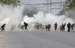 Des manifestants anti-coup d'Etat en Birmanie fuient les gaz lacrymogènes tirés par les forces de l'ordre, à Mandalay le 15 mars 2021