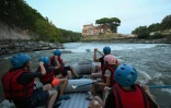 Des personnes naviguent en canot pneumatique sur le Tibre, passant devant l'île Tibérine, sur un tronçon du fleuve situé entièrement dans la zone urbaine du centre de Rome, le 14 août 2026