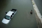 Un américain passe devant une voiture abandonnée alors que les eaux continuent de monter à Houston, le 28 août 2017