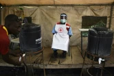 Un membre du personnel sanitaire veille à ce que les gens se lavent les mains pour lutter contre l'épidémie d'Ebola à la frontière entre la RDC et l'Ouganda, le 13 juin 2019. 
