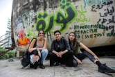 De jeunes Libanaises posant devant "L'oeuf", une structure emblématique en béton au toit oblong à moitié en ruines, recouvert de graffittis dont le mot "Revolution" en vert en arabe, à Beyrouth le 24 octobre 2019