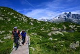 Des randonneurs marchent sur une structure nouvellement construite pour préserver la nature sur un sentier menant au lac Blanc, dans la réserve naturelle des Aiguilles Rouges, face au Mont Blanc, au-dessus de Chamonix, le 31 juillet 2023