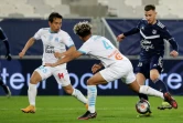 Les défenseurs de Marseille, le Japonais Yuto Nagatomo (g) et le Français Boubacar Kamara (c), disputent le ballon à l'attaquant de Bordeaux, Rémi Oudin, lors du match de Ligue 1 à Bordeaux, le 14 février 2021 