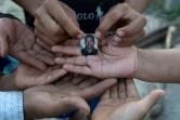 Une veuve et ses cinq enfants montrent le 23 juillet 2020 une photo de leur époux et père, Joaquin Barrera, mort du Covid-19 comme ses parents et deux de ses frères à Santiago Nonualco, au Salvador

