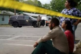 Des gens assis sur le trottoir à l'extérieur de l'école primaire Robb, à Uvalde au Texas, après la fusillade, le 24 mai 2022 ( AFP / allison dinner )