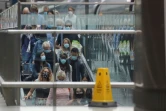 Des voyageurs, portant des masques de protection, prennent un escalator à leur descente de l'Eurostar en provenance de Paris, le 14 août 2020 à la gare St Pancras de Londres