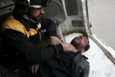 Un secouriste syrien assiste un homme blessé par un bombardement du régime sur la localité de Hammouriyé dans la Ghouta orientale, le 22 février 2018