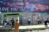Des habitants attendent un bus devant une affiche géante du chef d'état-major de l'armée pakistanaise Asim Mounir, dans une rue àRawalpindi, le 14 mai 2025 au Pakistan