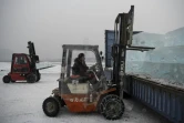 Des travailleurs chargent sur des camions des blocs de glace découpés dans la rivière Songhua, le 10 décembre 2019 à Harbin, en Chine