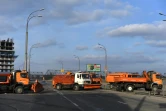 Des camions, habituellement utilisés pour déneiger les rues de Kiev, sont stationnés à un point de contrôle afin de ralentir les véhicules, sur une route de Kiev, le 25 février 2022