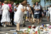 Une femme habillée de blanc se recueille, le 7 août 2016, devant un parterre de fleurs en hommage aux victimes de l'attaque meurtrière du 14 juillet