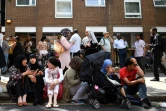 Des personnes affectées par le feu qui a ravagé la Tour Grenfell, assises sur le trottoir à l'extérieur d'un centre d'aide temporaire dans l'ouest de Londres le 14 juin 2017