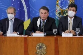 Le président brésilien Jair Bolsonaro (c) entouré de son ministre de l'Economie Paulo Guedes (g) et de la Santé Henrique Mandetta (d), lors d'une conférence de presse à Brasilia, le 18 mars 2020 