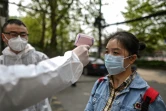 Un homme vérifie la température d'une habitante à Wuhan le 7 avril 2020