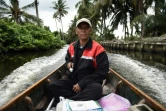 Nopadol, postier, distribue des lettres et colis aux habitants vivant sur les bords d'un canal dans la province de Bang Khun Thian, près de Bangkok en Thaïlande, le 17 juillet 2017