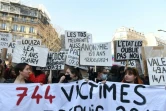Des femmes dénoncent sur des pancartes les victimes de violences conjugales en France, lors d'une manifestation le 8 mars 2022 à Paris pour la journée internationale pour les droits des femmes