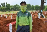 Le fossoyeur Junaidi Hakim devant des tombes de personnes décédées du coronavirus au cimetière de Pondok Ranggon, le 6 mai 2020 à Jakarta, en Indonésie