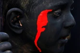 Un enfant, le visage et le corps peints en noir et rouge, se prépare à jouer le rôle d'un démon lors des célébrations de l'Achoura, à Noosh Abad, dans le centre de l'Iran, le 26 juillet 2023