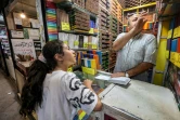 Photo prise le 22 mai 2023 montrant Mohammad Rafi, un vendeur de crayons de couleurs, discuter avec une jeune cliente dans son magasin, dans le bazar de Téhéran