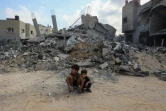 Des enfants sont assis devant une montagne de gravats après un bombardement à Nousseirat, dans le centre de la bande de Gaza, le 12 août 2024