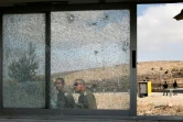 Des forces de sécurité israéliennes passent devant les vitres brisées du poste de contrôle de Har Adar, le 26 septembre 2017