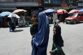 Une mère de famille en burqa avec ses enfants sur un marché de Kaboul, le 21 juillet 2021
