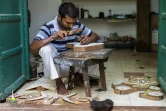 Un sculpteur grave des motifs d'impression sur des planches en bois dans l'atelier de la créatrice Brigitte Singh, le 2 juin 2022 à Amber, dans l'Etat du Rajasthan, en Inde