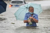 Un homme avance dans une rue inondée de Zhengzhou, placée en alerte rouge après des orages violents qui se sont abattus sur cette métropole du centre de la Chine, le 20 juillet 2021