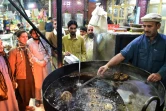 Un cuisinier fait griller des kebabs sous l'oeil de ses clients dans le quartier de Namak Mandi à Peshawar, le 13 décembre 2018