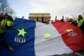 Des "gilets jaunes" brandissent un drapeau frappé d'étoiles et de trois dates : 1789, 1968, et 2018, à Paris, le 8 décembre 2018