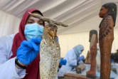 Une archéologue nettoie des statuettes en bois découvertes à Saqqara, lors d'une cérémonie, le 14 novembre 2020