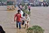 Des personnes pataugent sur une route nationale inondée après que la rivière Kosi ait débordé suite à de fortes pluies près de Rampur, dans l'État indien de l'Uttar Pradesh, le 20 octobre 2021