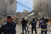 Des journalistes filment les décombres du bâtiment qui abritait les bureaux locaux de la chaîne qatarie Al-Jazeera et de l'agence internationale américaine Associated Press (AP) le 15 mai 2021 à Gaza