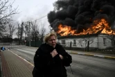 Une femme passe devant une maison en flammes après avoir été bombardée dans la ville d'Irpin, à l'extérieur de Kiev, le 4 mars 2022