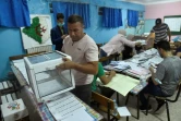 Des assesseurs comptent des bulletins de vote dans un bureau de vote en banlieue d'Alger, le 12 juin 2021
